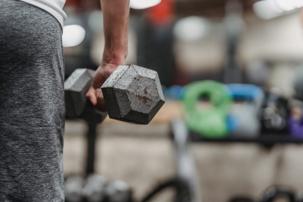 sportsman training with dumbbells in gym