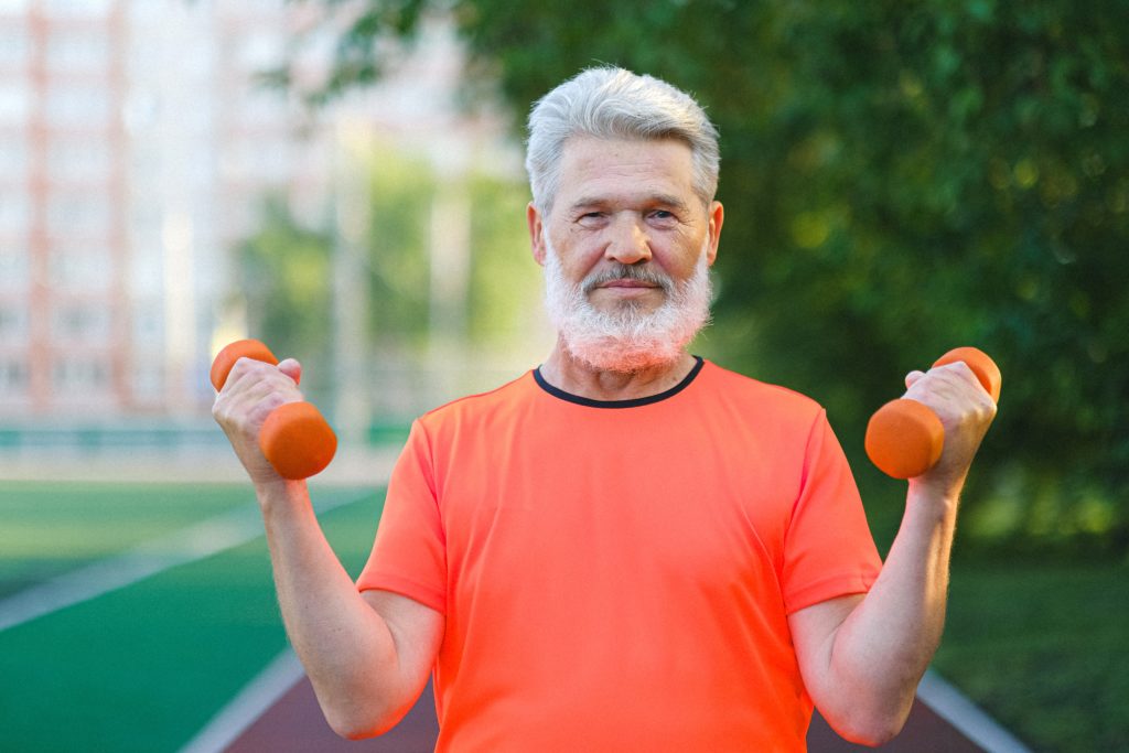 Cheerful aged sportsman doing sport exercise