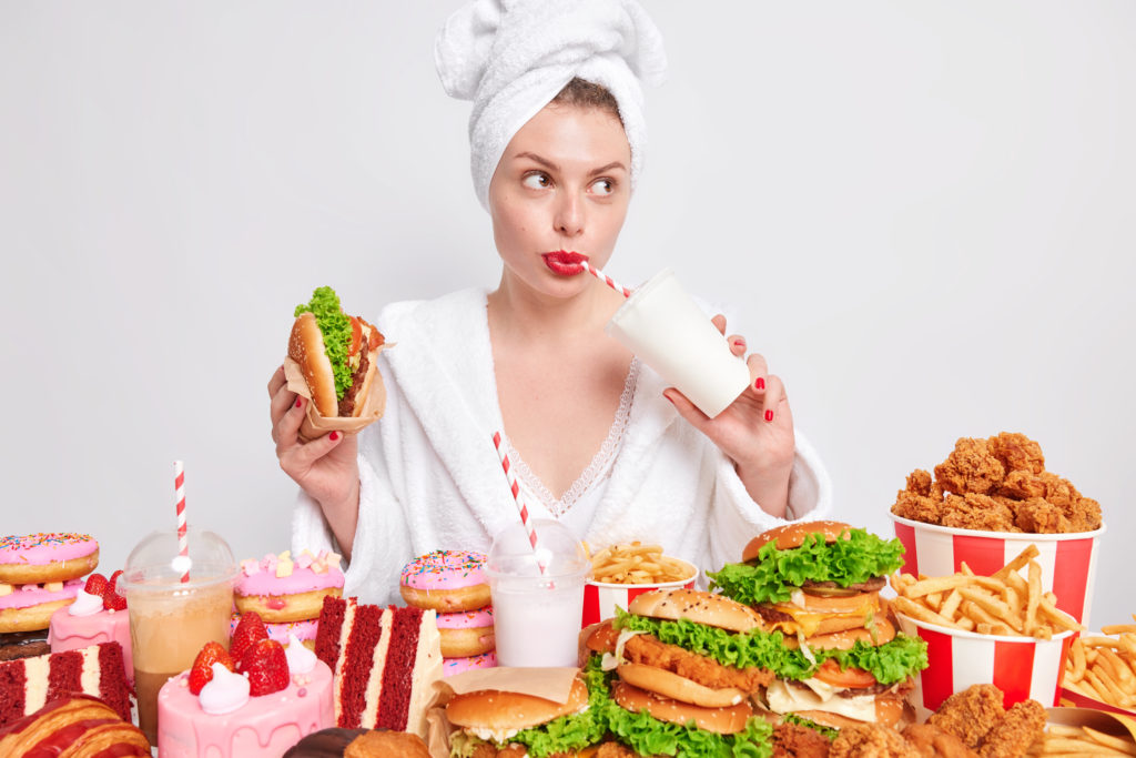 woman with red lips-drinks soda & eats burger-looks away addicted to fast food