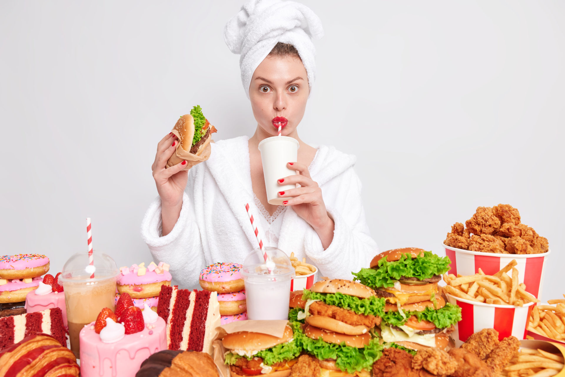 woman with red manicure & lips- wears domestic bathrobe towel head-drinks soda & eats junk food