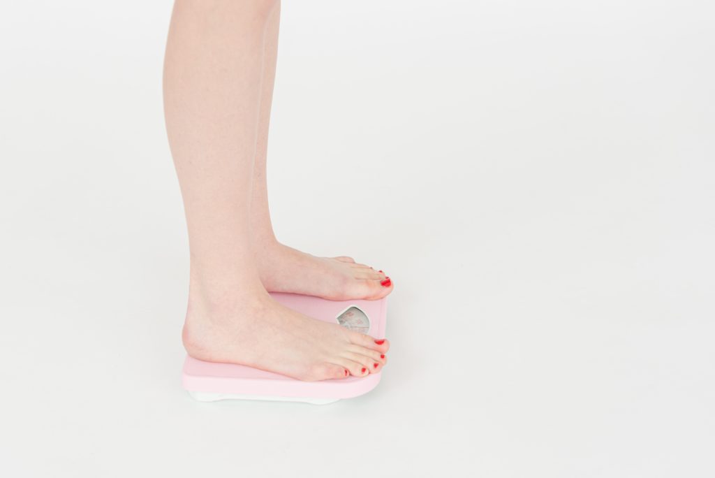 Woman checking weight on scales in studio