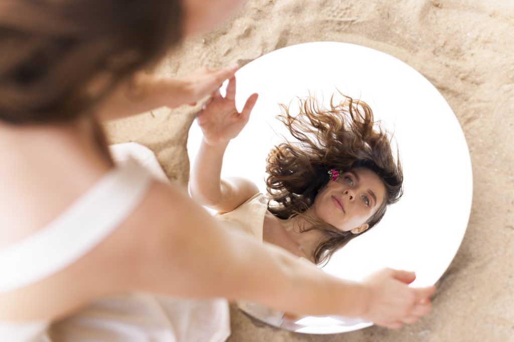 Young woman posing confidently outdoors with a round mirror