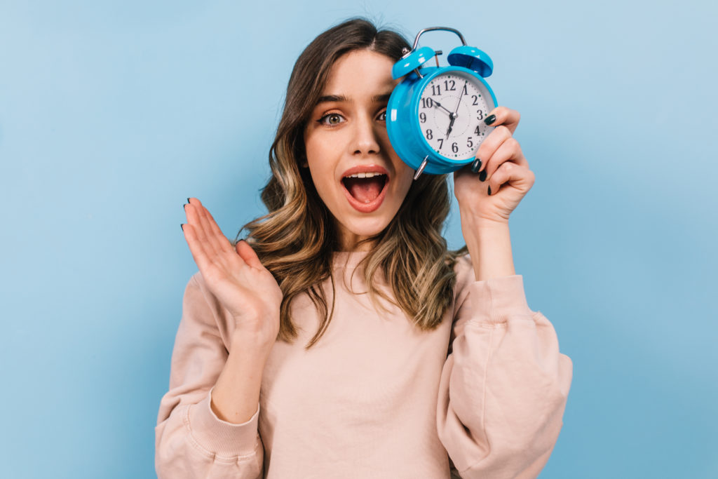 Woman with wavy hair holding clock