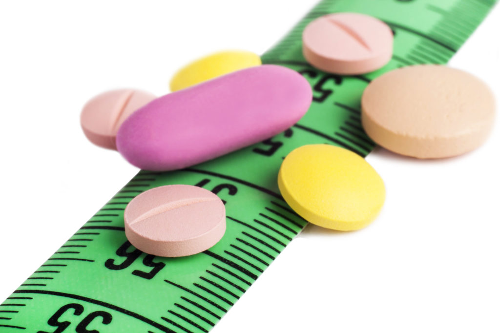 Closeup shot of the colourful drugs on the green tape measure on the white surface