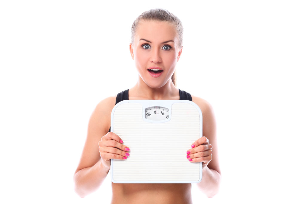 Beautiful fitness girl holding a scale