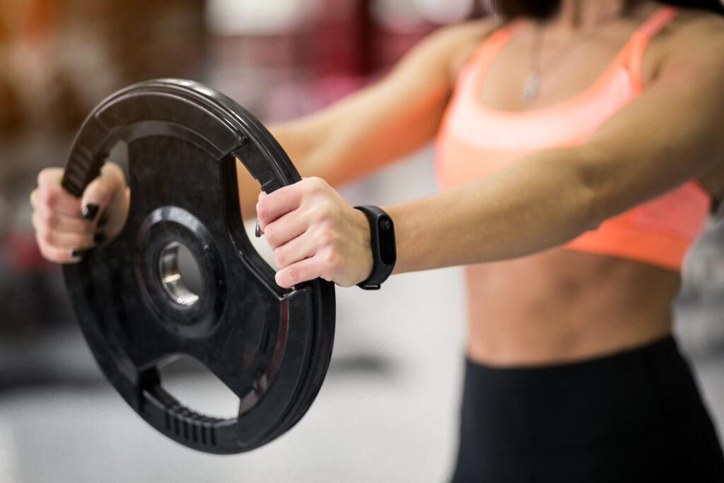 Woman at gym exercising with weight plate