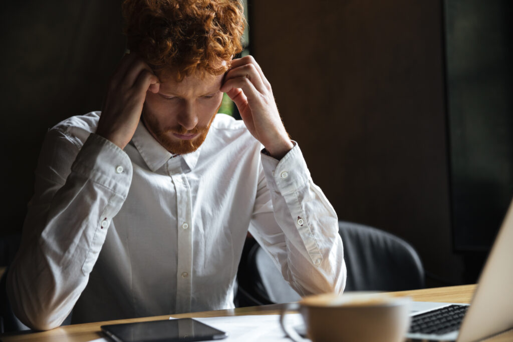 Photo of tired readhead businessman, touching his head, looking