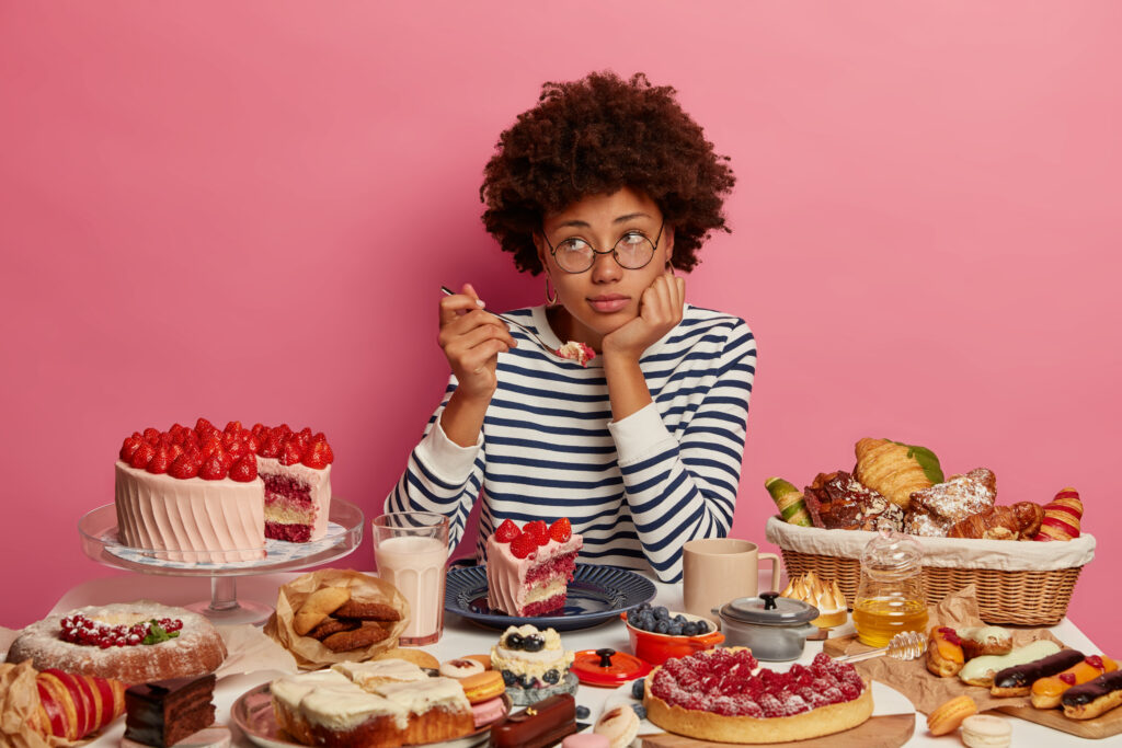 Young beautiful woman eating sweet food feeling sad